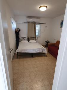 een slaapkamer met een bed en een rode bank bij Adam s apartments entrance to Neve Zohar in Neve Zohar