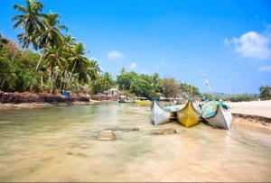 Tre barche sedute in acqua su una spiaggia di RONZ VISTA DA PRAIA a Calangute