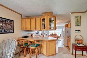 a kitchen with wooden cabinets and a kitchen island with chairs at Lyndonville Home with Fire Pit, Screened Patio and AandC in Waterport