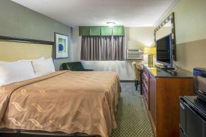 a hotel room with a bed and a flat screen tv at Roosevelt Hotel in Williston