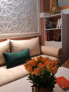 a couch with a vase of orange flowers on a table at Riad Johnboy in Marrakesh