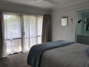 a bedroom with a bed and a large window at Kerikeri Central House in Kerikeri