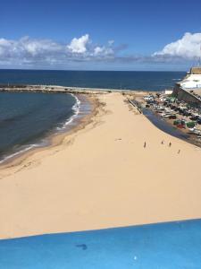 a beach with a group of people standing on the sand at Like-home Boa Onda House-T4-Ericeira center in Ericeira