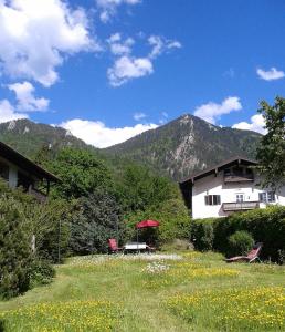 una casa en un campo con montañas en el fondo en Künstlerhaus Weissgerbergütl en Marquartstein