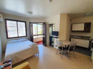 ein Schlafzimmer mit einem Bett und einem Tisch sowie eine Küche in der Unterkunft Manhattan Apart Hotel in Porto Alegre