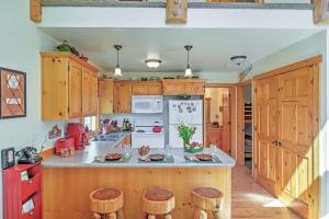 a kitchen with wooden cabinets and wooden stools at Bright Klamath Falls Cabin with Deck and Mtn Views! in Klamath Falls