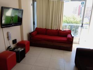 sala de estar con sofá rojo y TV de pantalla plana en Departamento Luxor en Villa Carlos Paz