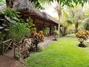 a resort with a grass roofed building with a yard at Hotel Manavai in Hanga Roa