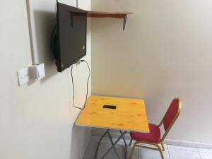 a wooden table with a tv and a red chair at Dream Palace Hotel Mbale in Mbale