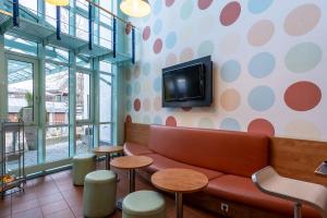 a waiting room with a couch and a tv on a wall at Hotel Holledau in Geisenhausen