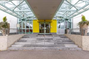 ein Glasgebäude mit einer Treppe, die zu einer Tür führt in der Unterkunft Hotel Holledau in Geisenhausen