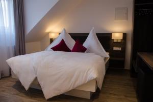 a bedroom with a white bed with red pillows at Hotel Restaurant Lamm in Mönsheim