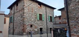 un edificio de piedra con ventanas verdes y una puerta en Casa Nostra Camaiore, en Camaiore