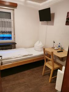 カイザースラウテルンにあるSee Lord Hotelのベッドとデスクが備わる小さな客室です。