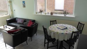 - un salon avec une table, des chaises et un canapé dans l'établissement Duinnachtegaal, à Egmond aan Zee
