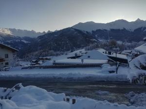 un pueblo cubierto de nieve con montañas en el fondo en Apart Laudes, en Ladis