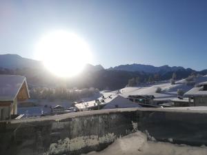 Blick auf ein schneebedecktes Dorf mit der Sonne im Hintergrund in der Unterkunft Apart Laudes in Ladis