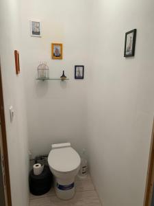 a white bathroom with a toilet and pictures on the wall at Accueil chaleureux in Crannes-en-Champagne