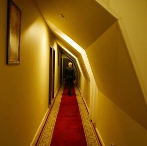 モスクワにあるMarkell Hotelの赤絨毯を敷いた廊下を歩く男