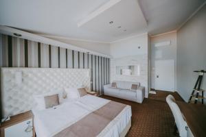a bedroom with a large white bed and a couch at Rooms Nadia in Stara Baška