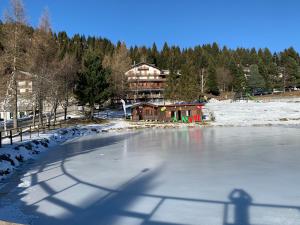 a frozen pond in front of a house in the snow at BELLISSIMO BILOCALE RESIDENCE SKY PARADISE MT.1400 MONTE PORA in Malga Alta
