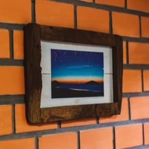 un marco de imagen colgando de una pared de ladrillo en Punta Canoa cabanas, en Praia do Rosa