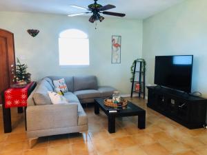 a living room with a couch and a flat screen tv at Mariposa Beach House in Humacao
