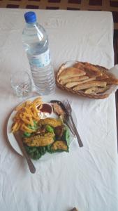 a plate of food with french fries and a bottle of water at Sahara Desert Camp in Adrouine