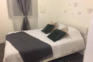 een bed met zwarte en witte lakens en groene kussens bij F3 agréable et calme in Château-Thierry