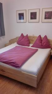 Elle comprend un grand lit avec des draps et des oreillers violets. dans l'établissement Ferienwohnung Wohlesser, à Annaberg-Lungötz