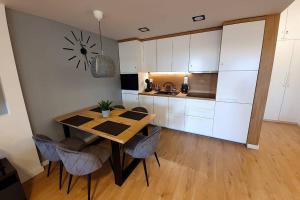 kuchnia ze stołem i krzesłami oraz zegarem na ścianie w obiekcie Duplex apartment Morsztynowska w Krakowie +12 zdjęć