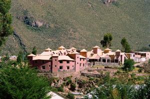 um grupo de edifícios numa colina com uma montanha em Pozo del Cielo em Chivay