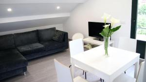 sala de estar con sofá negro y mesa blanca en Apartamentos AUGA, en Fene