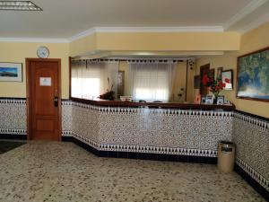 a lobby with a tile wall with a clock on the wall at Hotel Catalán Puerto Real in Puerto Real