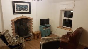 a living room with a fireplace and a television at Cosy Cottage on the Causeway coast and Glens in Ballycastle