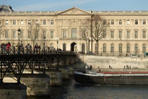 a bridge over a river in front of a large building at Louvre Penthouse PadATerre Owner Direct since 1999 in Paris