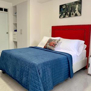 a bed with a blue blanket and a red headboard at Edificio saintjoseph in Cali