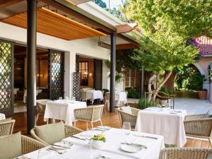 um restaurante ao ar livre com mesas e cadeiras brancas em Hotel Bel-Air - Dorchester Collection em Los Angeles