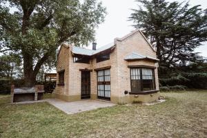 una casa de ladrillo con un banco en un patio en Los Catires, en Sierra de la Ventana