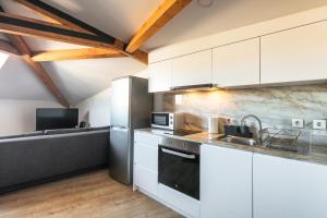 a kitchen with white cabinets and a couch at Solar Studio Campanhã in Porto