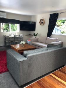 ein Wohnzimmer mit einem Sofa und einem Tisch in der Unterkunft Kānuka Cottage - Tranquil and relaxing in Akaroa