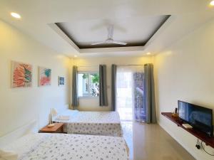 a bedroom with two beds and a flat screen tv at Villa del OZ Resort in Panglao +37 photos