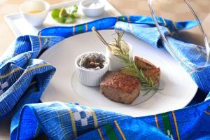 un plato blanco con un trozo de carne sobre una mesa en THE HIRAMATSU HOTELS & RESORTS GINOZA OKINAWA, en Ginoza