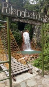 une cascade en arrière-plan avec un panneau en avant dans l'établissement Pulangbato Falls Mountain Resort, à Dumaguete
