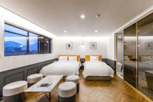 釜山にあるBrowndot Hotel Sasang Reneciteのベッド2台とテーブルが備わるホテルルームです。