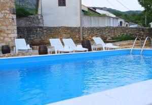Grižane的住宿－Villa Kate - cosy place in the nature，蓝色的游泳池,配有白色的椅子和墙壁