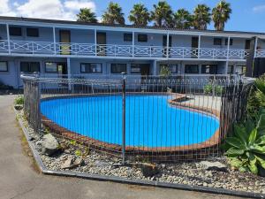 a fence around a swimming pool in front of a building at Walton Park Motor Lodge in Warkworth