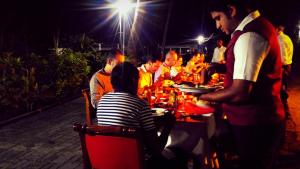 a group of people sitting at a table at night at Lake Side Tourist Inn in Tissamaharama