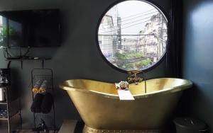 ein Badezimmer mit einer Badewanne und einem runden Spiegel in der Unterkunft NIL BKK in Bangkok