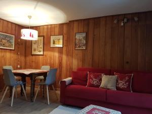 a living room with a red couch and a table at Appartamenti dei Giardini in Courmayeur